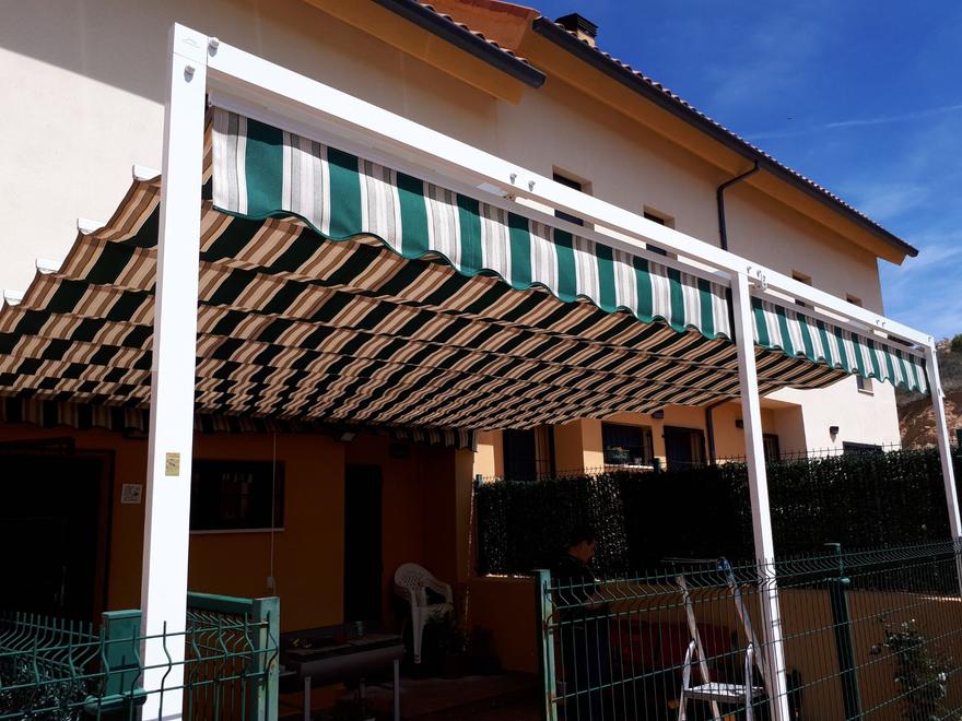Toldo de rayas verdes y blancas en el porche de una vivienda