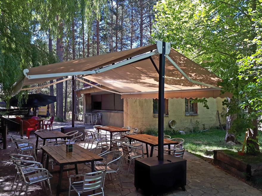 Toldo beige sobre la terraza de un bar entre pinos