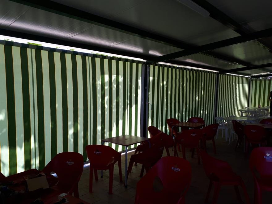 Toldos verticales de rayas verdes en una terraza con mesas