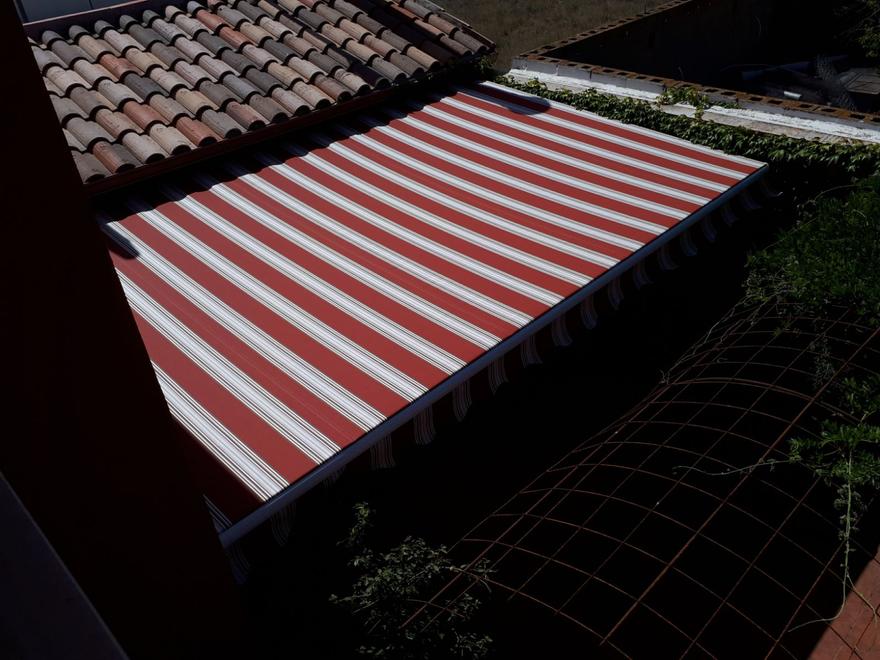 Toldo de rayas rojas y blancas sobre un patio